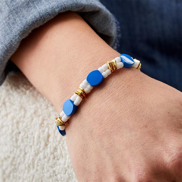 wrist with blue, gold and white bead bracelet